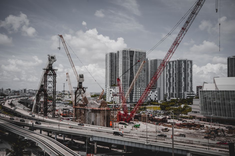 Ações do GDF — A cityscape featuring high-rise buildings and a construction site with cranes under a cloudy sky.